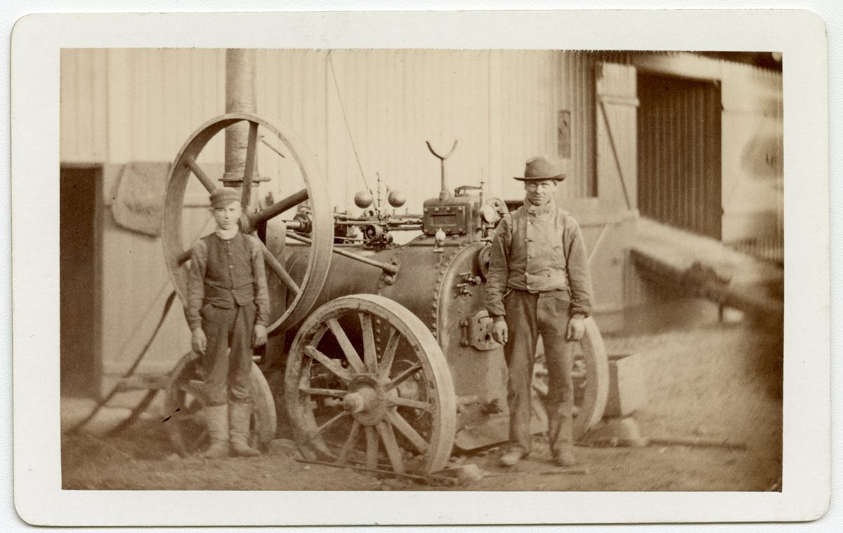 Foto av gutt og mann foran en lokomobil designet av Clayton & Shuttleworth. 

Trolig et av de tidligere modellene firma produserte, en så kalt "portable Steam Engine" som alt var i produksjon på midten av 1850-tallet