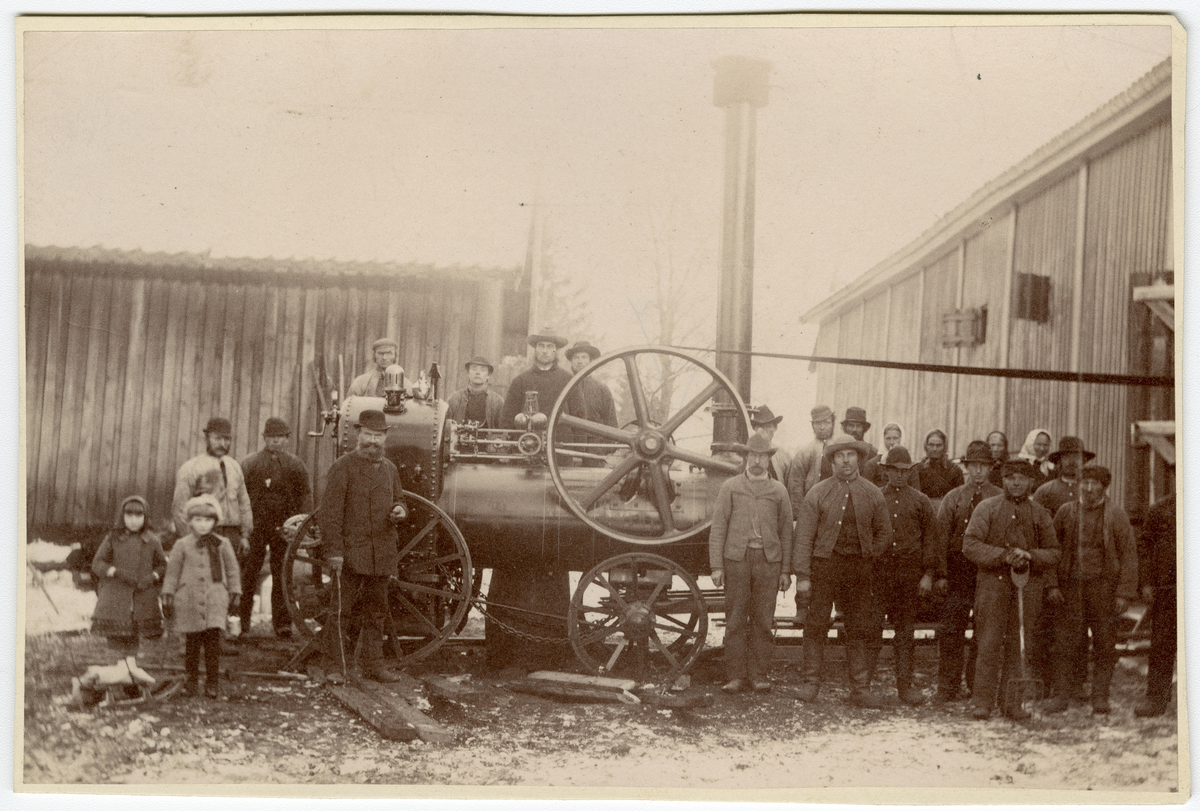 Foto av arbeidere foran en lokomobil prosudert av Richard Hornsby & Sons

Foran som nr. 5 fra venstre står byggmester Nestor Malthe (med skjegg og spaserstokk). Foto tatt i 1884