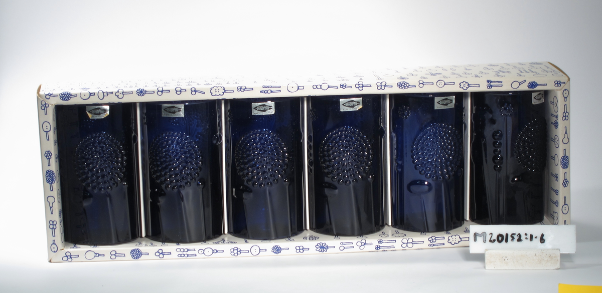 "Flora" formgiven av Oiva Toikka. Blått glas. Cylinderformad med reliefmöster av stiliserade blommor.

Ligger i originalförpackning.