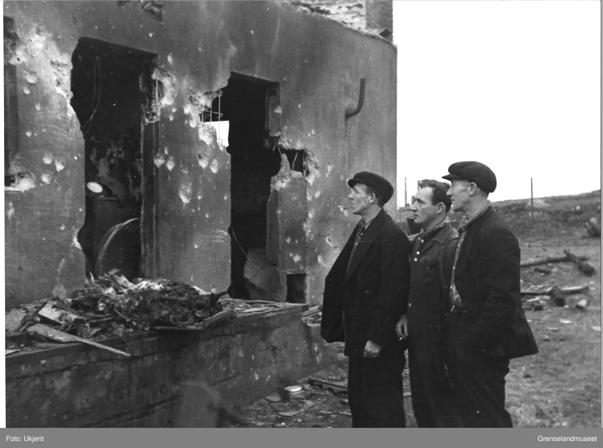 Tre menn undersøker en utbrent bygning i ruinene av Kirkenes. Bildet ble tatt etter at Sovjetunionens Røde Arme frigjorde Kirkenes høsten 1944.