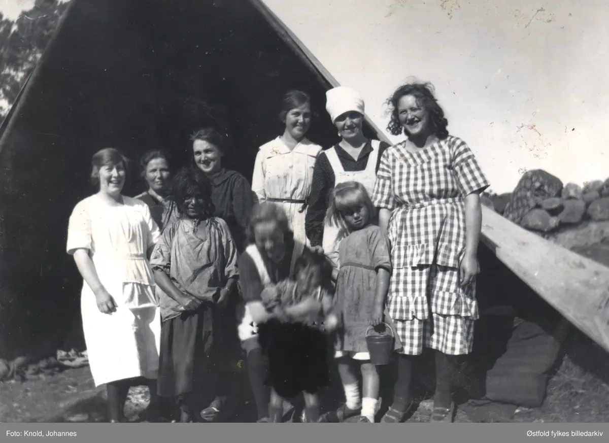 Skjebergkvinner på besøk i leiren til romer (tidligere kalt sigøynere), Borgen mellom ved Iseveien i Skjeberg. To av rom-barna er med på fotoet. Synnøve Hovland og Gudrun Lagerta Knold er med på bildet.
Asbjørg Olaisen som er født i 1934, kan huske at det var sigøynere på Nygård ved Iseveien da hun var ganske liten. Hun mener året kan ha vært 1937.