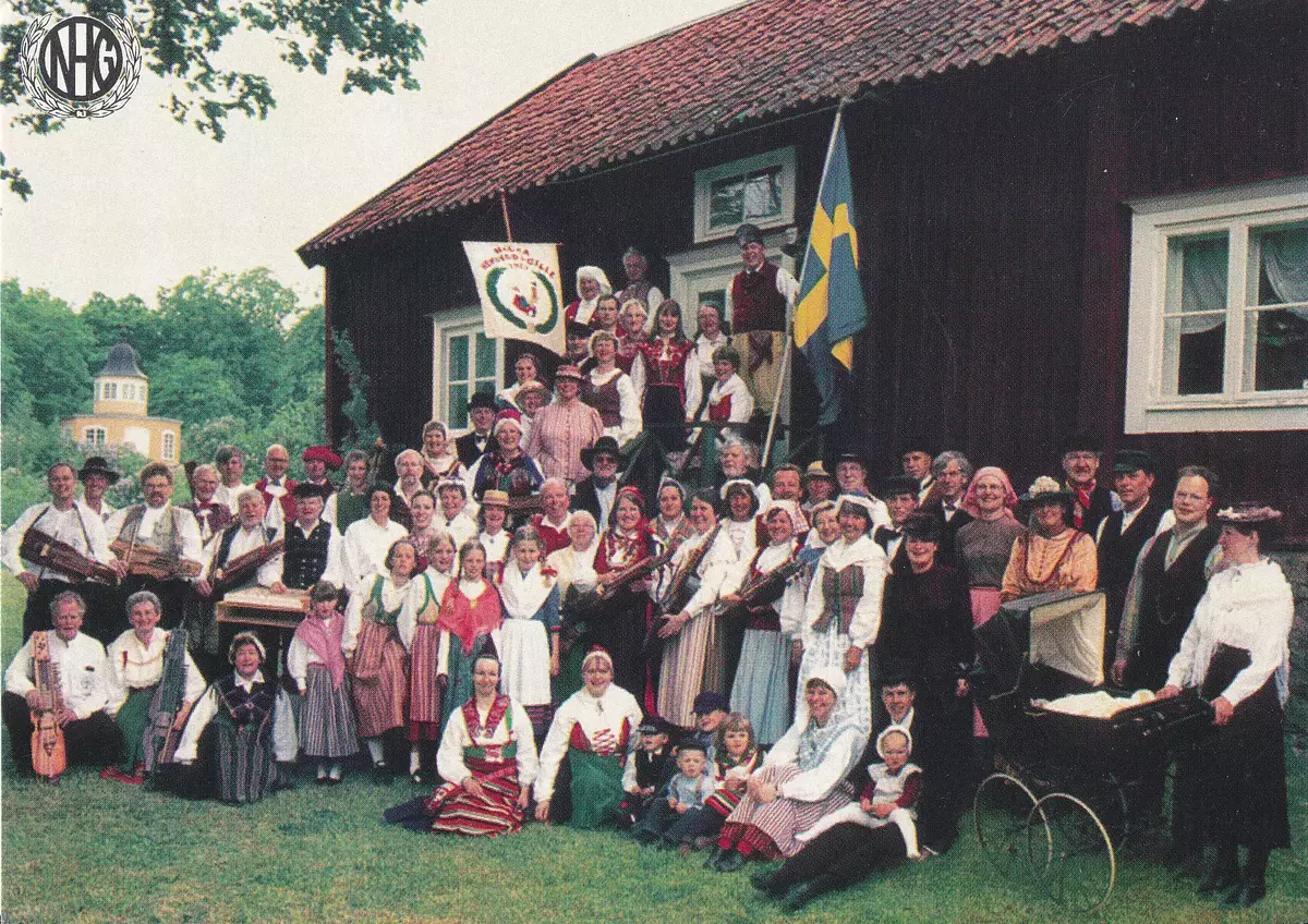 Nacka hembygdsgille utanför Nacka hembygdsmuseum i Stora Nyckelviken, år 1990. Nedre raden från vänster: 1. Tord Stjernqvist 2. Anne-Marie Hagberg 3. Monika Sahlberg-Eriksson 4.                        5. Anita Rinnbäck 6. Johanna Larsson 7. Henrik Larsson 8. Jonas Rinnbäck 9. Patrik Hellberg 10. Kristin Hellberg 11. Marie Hellberg 12. Elin Österberg 13. Björn Österberg Mellersta raden från vänster: 14.                15. Frida Eriksson 16.                                         17.                                                               18. May-Britt Dahlström 19. Marianne Håkansson 20. Vera Jonsby 21. Maja Salava 22. Anita Aasa 23. Bror Aaasa 24. Anja-Riitta Sjöberg 25. Märta Persson 26. Solveig Palmer 27. Ivan Persson 28. Björn Lindahl 29. Ingegerd Blomfeldt 30. Bo-Ingemar Darlin 31. Bengt Palmer 32. Eva Zachrison 33. Margareta Westlund 34. Erik Zachrison 35. Bertil Westlund 36. Peter Hellberg 37. Ingela Österberg Översta raden från vänster: 38. Bo Nilsson 39. Jan Söderberg 40. Jan Lundqvist 41. Sture Blomqvist 42. Hans Zetterberg 43. Bo Karlsson 44. Hans Åbom 45. Sten Larsson 46. Jan Eneqvist 47. Bertil Svensk 48. Monique Karlsson 49. Rune Hemlin 50. Frida Eriksson 51. Rune Wenngren 52. Anita Wangel 53. Bror Fröderberg 54. Siv Österberg 55. Göran Wangel 56. Inga-Britta Lundqvist 57. Åke Fred 58. Solveig Fred 59. Ulla Knutsson 60. Maud Blom 61. Gun Svensson 62. Ulla Blomqvist 63. Hans Blom 64. Karin Hagberg 65. Anna Jonsby 66. Gerd Björklund 67. Leif Jonsson. 68. Barbro Jonsson. 69.                                                Vykort, Stockholm 1999, T-tryck AB. 