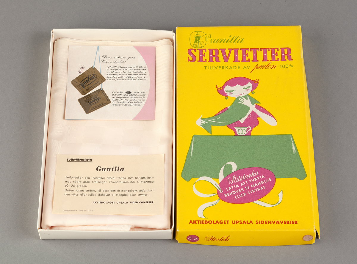 Originalförpackning, rektangulär kartong av papp med flerfärgstryck i grönt, cerise och vitt mot gul botten. Bild av en kvinnofigur som stryker över en bordsduk med ena handen. Firmamärke med Gunillaklockan. Text: BORDDUK AV PERLON 100 %. SLITSTARK... Inuti kartongen instruktionsblad och tvättföreskrifter.