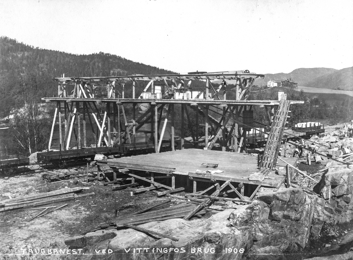 Starten på bygging av taubanen over elva:.
I bakgrunnen ser man sidesportet på Holmestrand-Vittingfossbanen. 
Fotograf Albert Wüller (1877-1944) , ingeniør fra Nyland Mek. Leverandør av maskiner til bruket. Bodde sammen med familien på stedet i lengre tid.