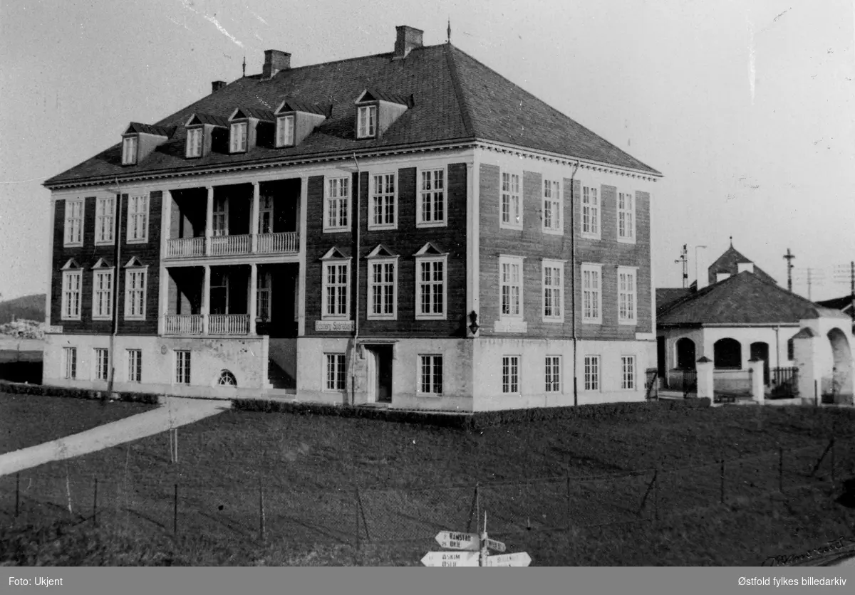Heggin kommunelokale 1927 i Eidsberg. Skilt på huset: Eidsberg Sparebank. Veiskilt i forgrunnen.