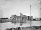 Linköpings sockerfabrik 1905. Den bastanta anläggningen uppfördes i hast och stod klar under fotoåret. Notera förgrundens vattenspegel. Den så kallade Rudsjön hade bildats som en följd av höjt vattenstånd i Stångån efter att dammanläggningen i Nykvarn byggts 1867. Den lilla sjön torrlades kort efter bildens tillkomst.