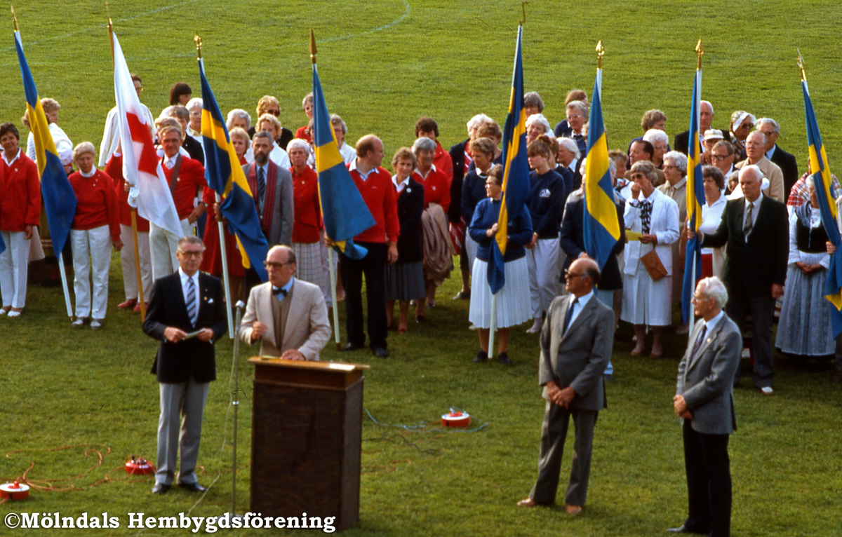 Nationaldagsfirande på Kvarnbyvallen i Trädgården, Mölndal, den 6 juni 1985. På Nationaldagen utdelade Berthold Wiklund och kommunfullmäktiges ordförande Sven Olsson förtjänsttecken till Erik Gustavsson, till vänster, och Rolf Johansson.