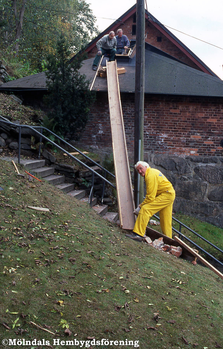 Götaforsliden i Mölndals Kvarnby, år 2002. Tegelstenen tas ur syratornet Gomorra, Götaforsliden 14. På marken, i Royens trappor, ses Bernt Andersson. På taket Frode Lyngsaa och Tage Bernhardson.