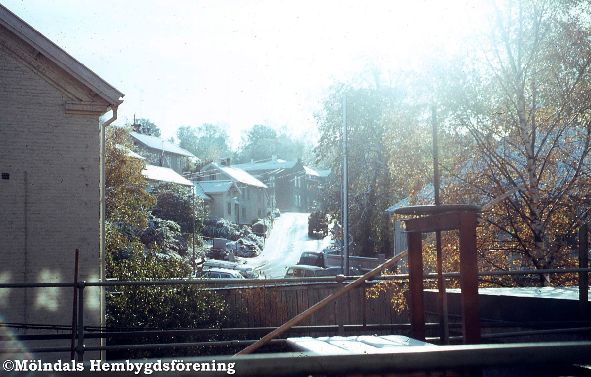 Till vänster ses del av gaveln på byggnaden gamla Sveaborg, Kvarnfallet 27, Forsåkergatan 2A i Mölndal, 1970-tal. Byggnaden användes från början för kvarnverksamhet, senare föreningslokal och bostäder. Tillhörde pappersbruket Papyrus. Byggnaden revs 1976. I bildens mitt ses även gamla polishuset med adress Forsåkersgatan 19.