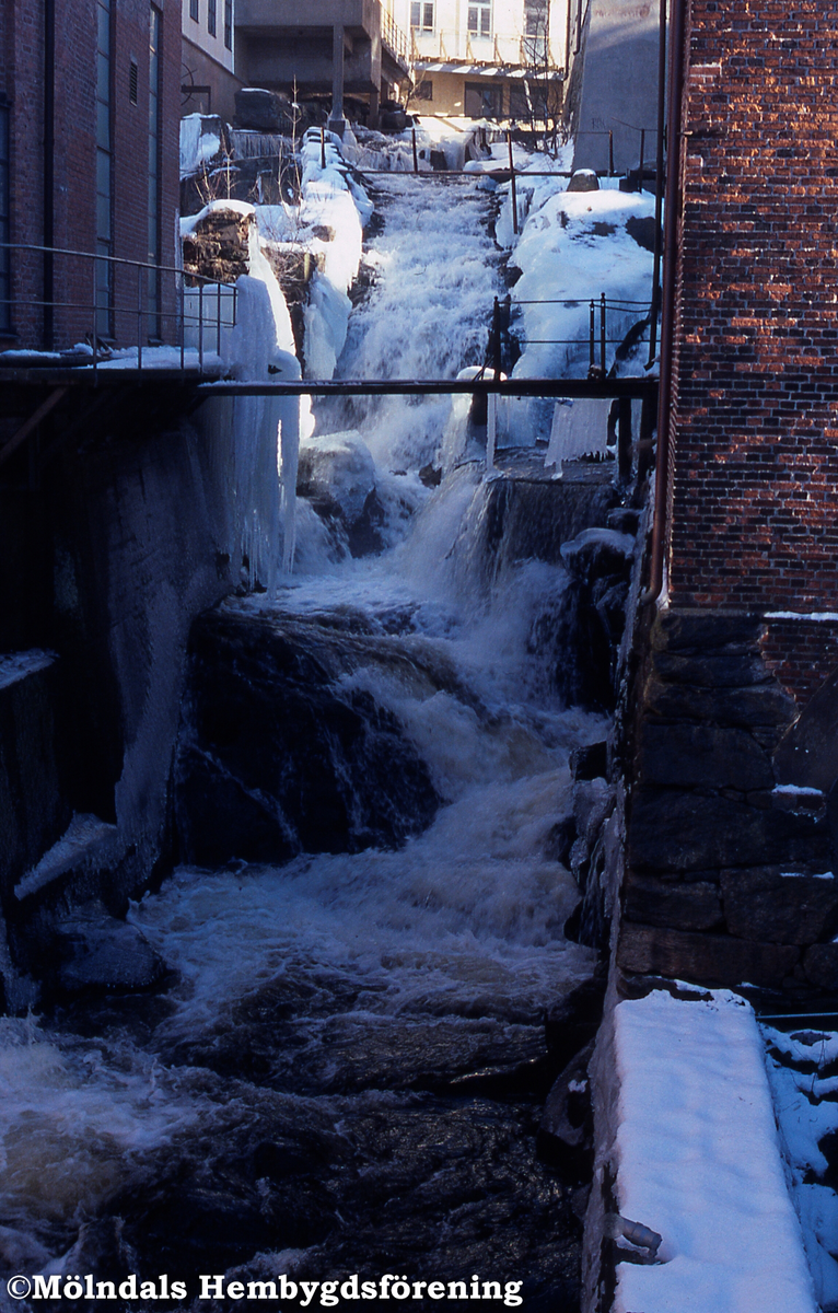 Mölndals Kvarnby i februari 2003. Mölndalsfallet i vinterskrud. Industribebyggelsen ses på båda sidor om forsen. Närmast till höger Lilla Götafors. Längs upp i mitten byggnaden Strumpan.