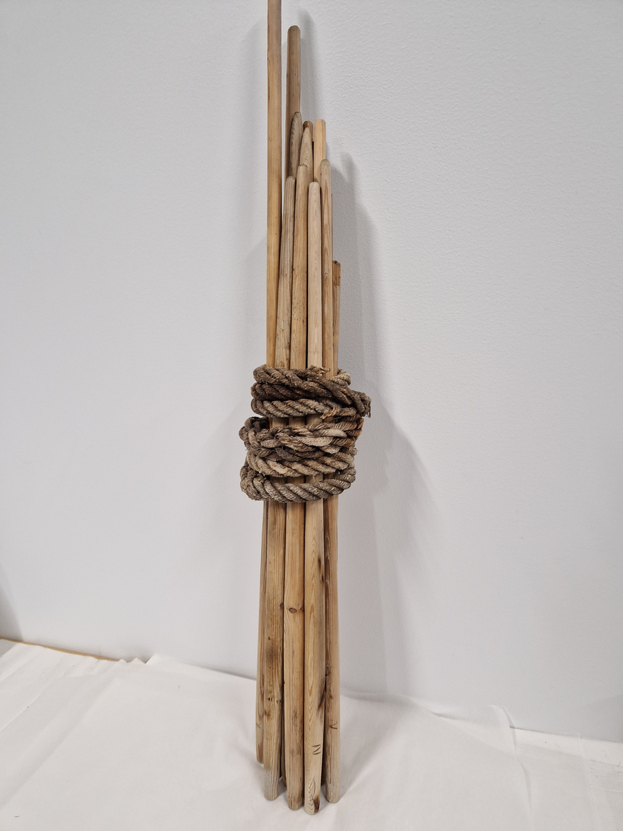15 lange pinner som er dreid, 1 er knekt på tuppen, bundet sammen med et hamptau