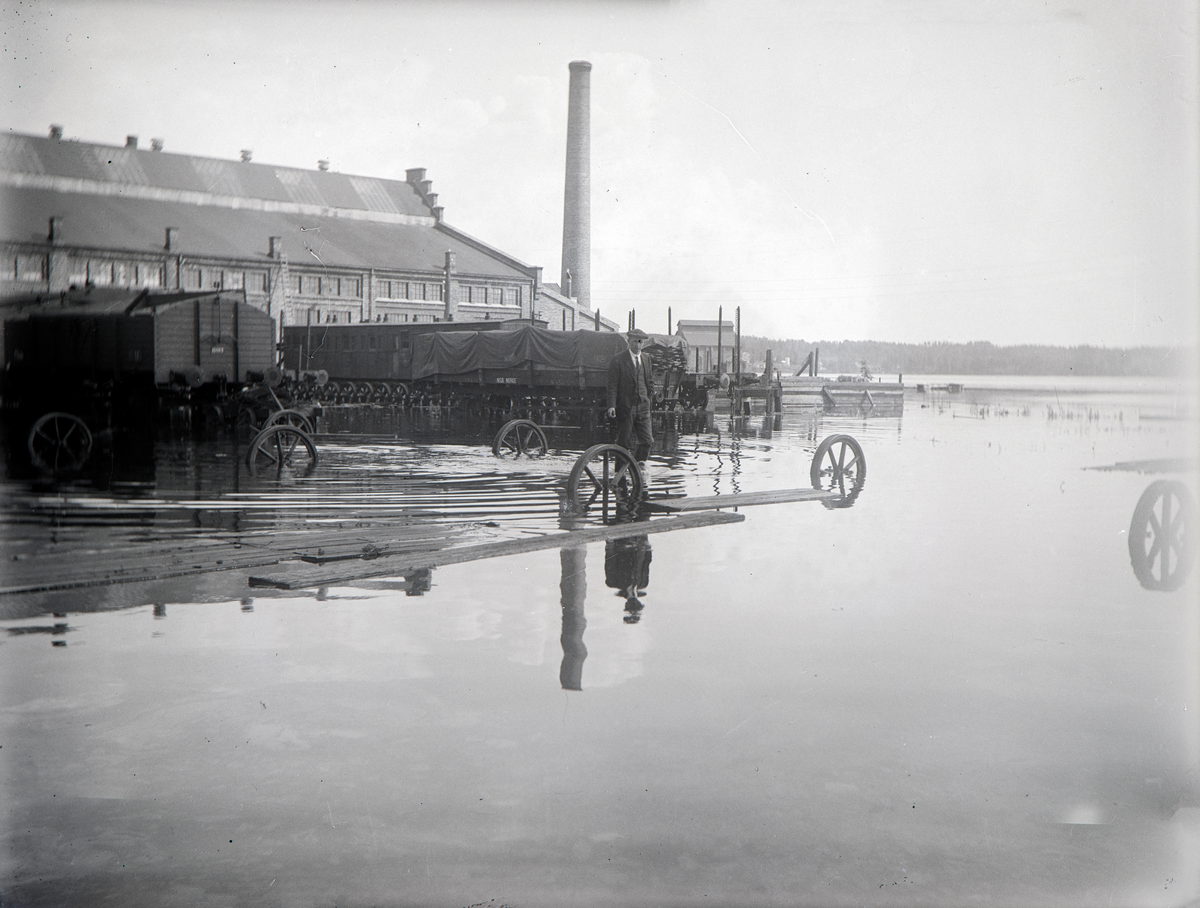Hamar, Espern, Hamar Jernbaneverksted, Mjøsflommen 1927 på fabrikktomta, 6. juli vannstand 8,10 meter, mann ved jernbanevogner,