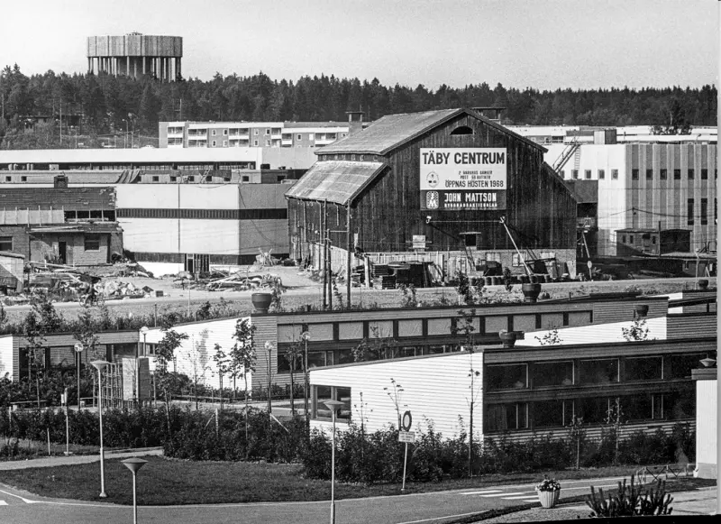  Under uppbyggnad av Täby Centrum användes Tibble gårds lada som magasin. Gammalt och nytt möts. Vattentornet i Ensta i bakgrunden.