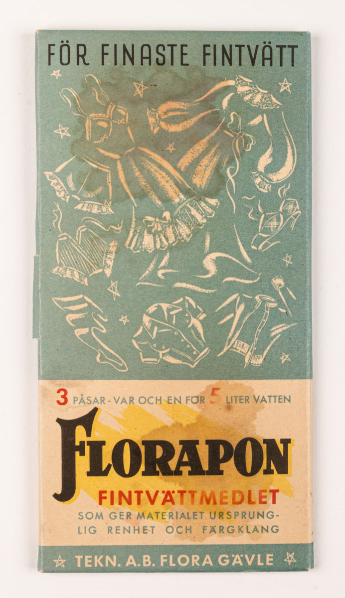 Tvättmedelsförpackning av papp. Obruten, innehåller tvättmedel. Platt, rektangulärt omslag. Tryck i blått, svart och rött på vit botten. På framsidan text: "Florapon fintvättmedlet" och "3 påsar - var och en för 5 liter vatten" samt "TEKN. A.B. FLORA GÄVLE" m.m. samt diverse klädesplagg. På baksidan finns "Dockan Flora", urklippsdocka med diverse kläder och medföljande hund "Fido".