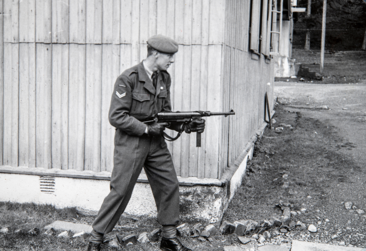 Korporal Odd Aspeli i militæruniform og med våpen, maskinpistol MP40.  Han tjenestegjorde hovedsakelig på Sessvollmoen ved Jessheim. Men hadde også en periode i Bergen. Han endte sin militære kariære som Fenrik.