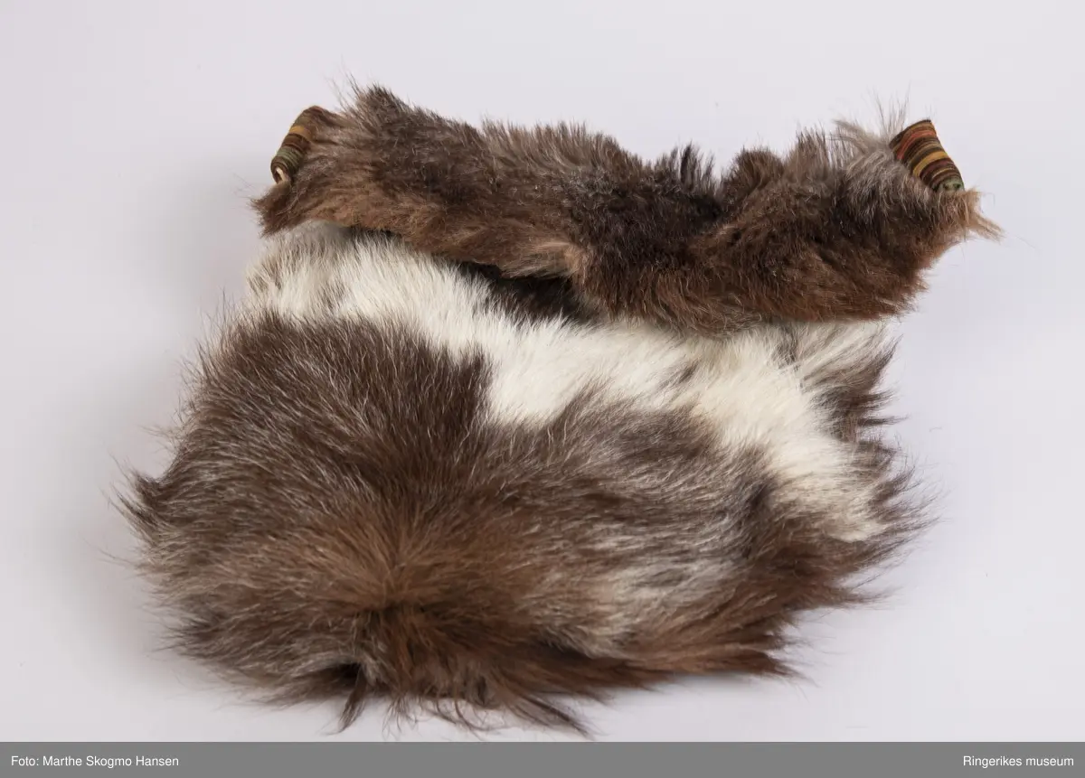 Sovepose til dokker. Posen er sydd av geiteskinn, som er brunt og hvitt. Innvendig er den foret med stripete cordfløyel. Posen ble sydd av Edel Gusgaard (1911-2000).