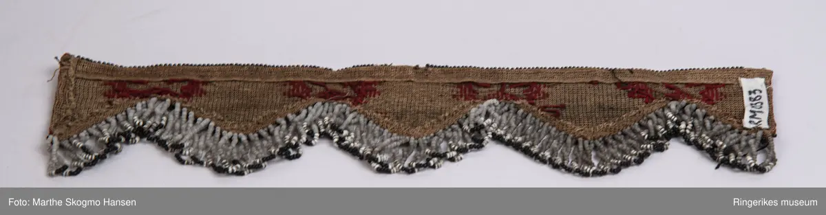 kartusjeer og utfyllende bord i mellom, hengende løkker av perler fra hver spiss.