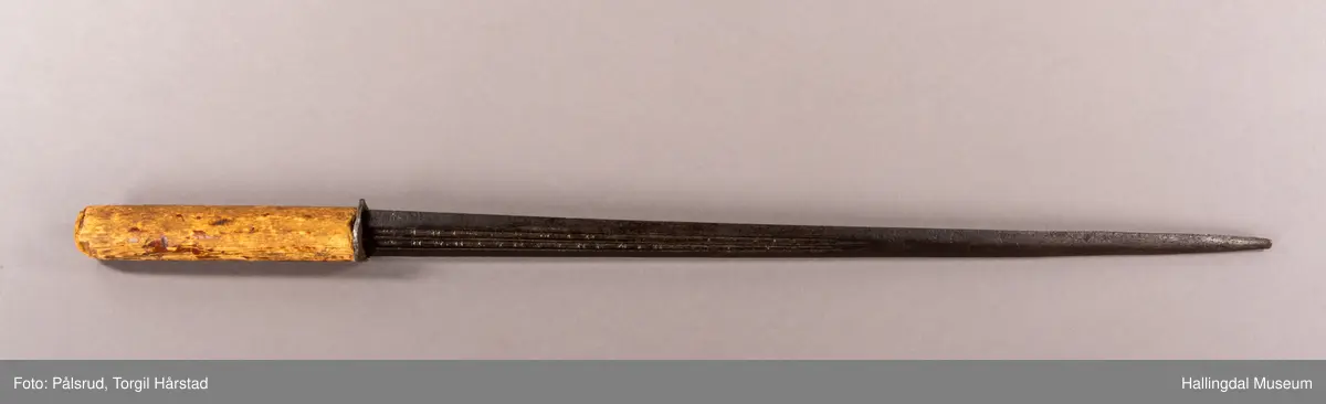 En stilett, eller dolk, fra Spania, fra 1600 tallet. Antatt omsmidd og senere påsatt et grovt håndtak i tre. 
Dette stilettbladet er antagelig laget av eller i verkstedet til Juan Martinez i Toledo, Spania. 