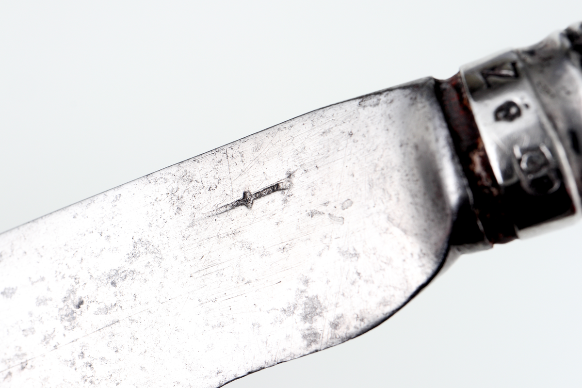 Kniv av silver.
Skaftet är tillverkat av pressat eller drivet silver, med dekor av pärlstavsbårder och längsgående räfflor. Stämplar (något svårtydda) på bladets infästning.

Inskrivet i huvudbok 1903.
