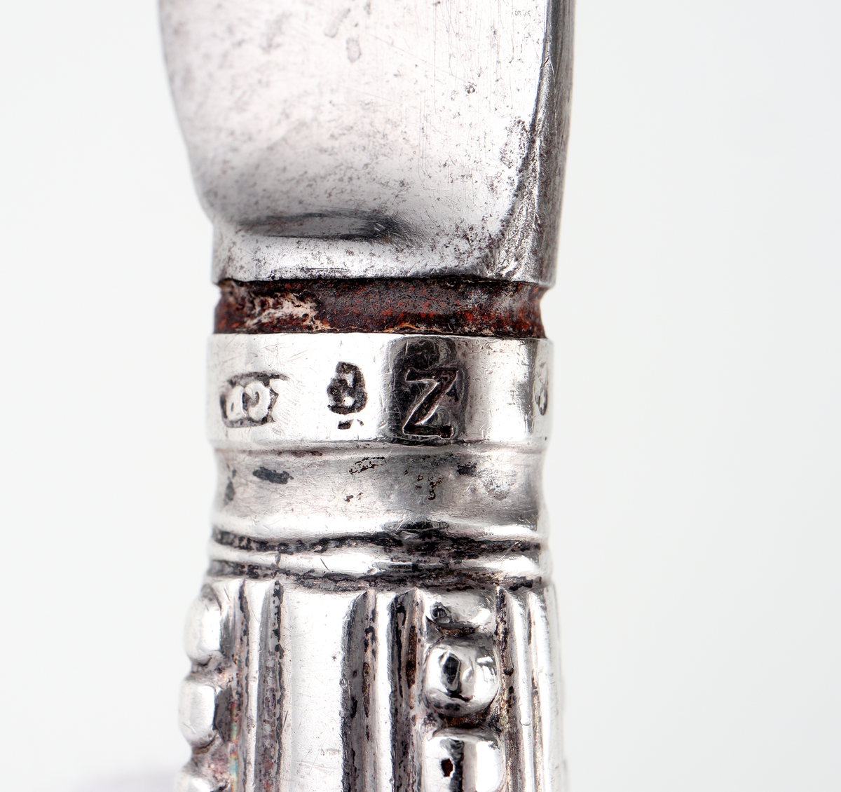 Kniv av silver.
Skaftet är tillverkat av pressat eller drivet silver, med dekor av pärlstavsbårder och längsgående räfflor. Stämplar (något svårtydda) på bladets infästning.

Inskrivet i huvudbok 1903.