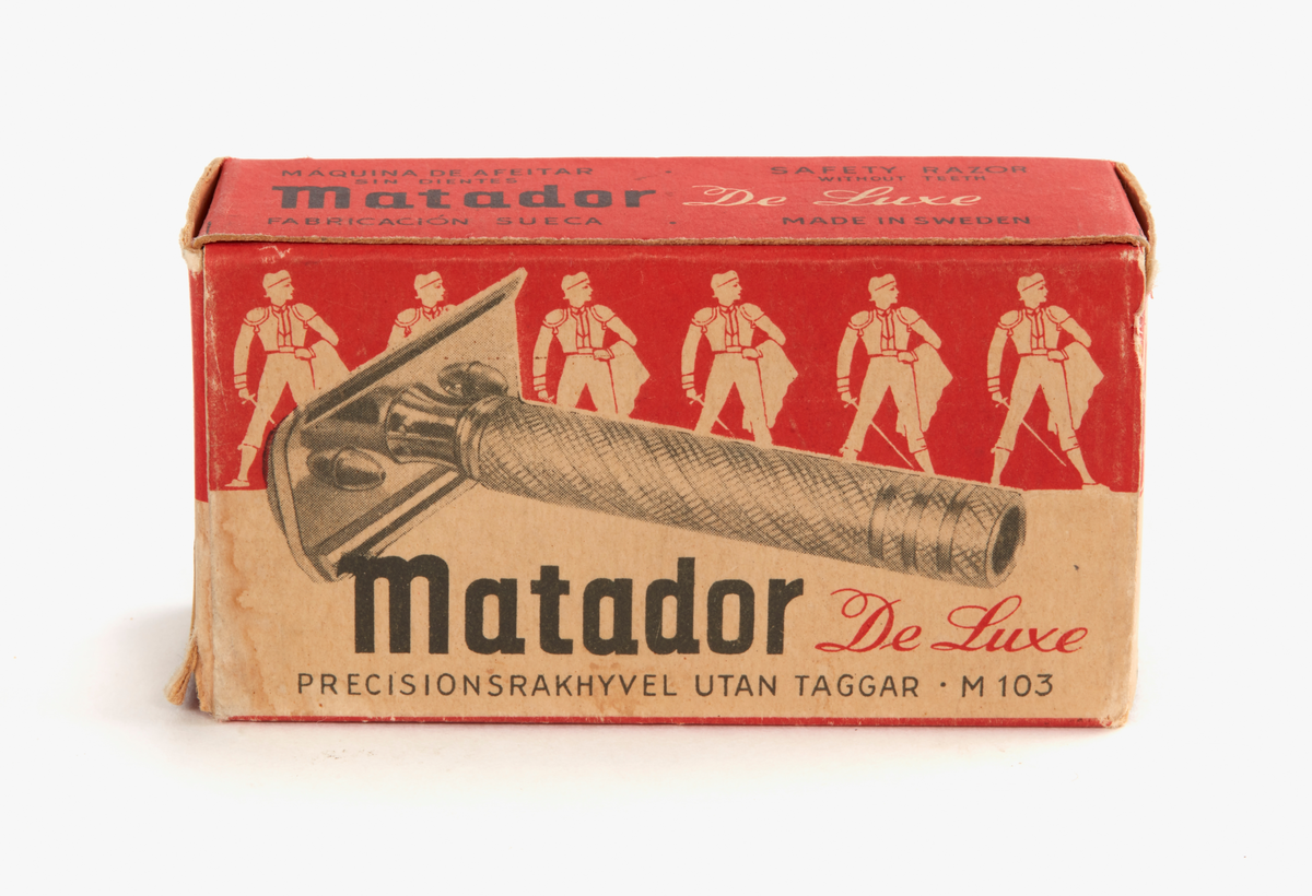 Rakhyvel av vitmetall, fabrikstillverkad.

Av märket: Matador. I orginalförpackning med tillhörande rakblad. Kartongen med tryckt text och mönster av stiliserade män.

Köpta 1976-09 på Faluboden, Slaggatan, Falun.