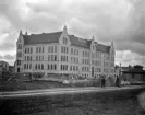 Linnéskolan i Linköping kunde invigas 1898 och tillkommen före stadens elektrifiering var standarden enkel. Skolan saknade även gymnastikal. Detta till trots blev den nya läroanstalten ett verkligt lyft för stadens skolväsen. Byggnadens yttre gavs ett monumentalt formspråk med gesimser, dekorativa ankarslutar och artikulerade gavelrösten. Efter en eldsvåda 1923 fick skolan ett enklare uttryck. Bilden är odaterad men närmast omärkbart pågår grundläggningen av Klostergatan 68 i motivets förgrund. Huset stod inflyttningsklart 1903.
