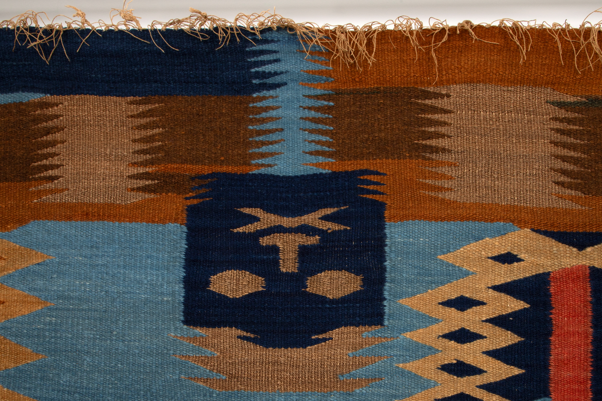 Ornamentalt, dekorativt, nonfigurativt motiv. Gule, oransje, brune og mørkeblå ornamenter på lyseblå bunn. Taggete formspill som optisk synes å "vibrere", kanskje som visuelt tordenskrall (jfr. tittelen). I et av de øvre feltene er verkets tittel og kunstnerens initialier vevd inn. En av de ornamentale formene i øvre del kan alternatitvt leses figurativt som et ansikt snudd på hodet.