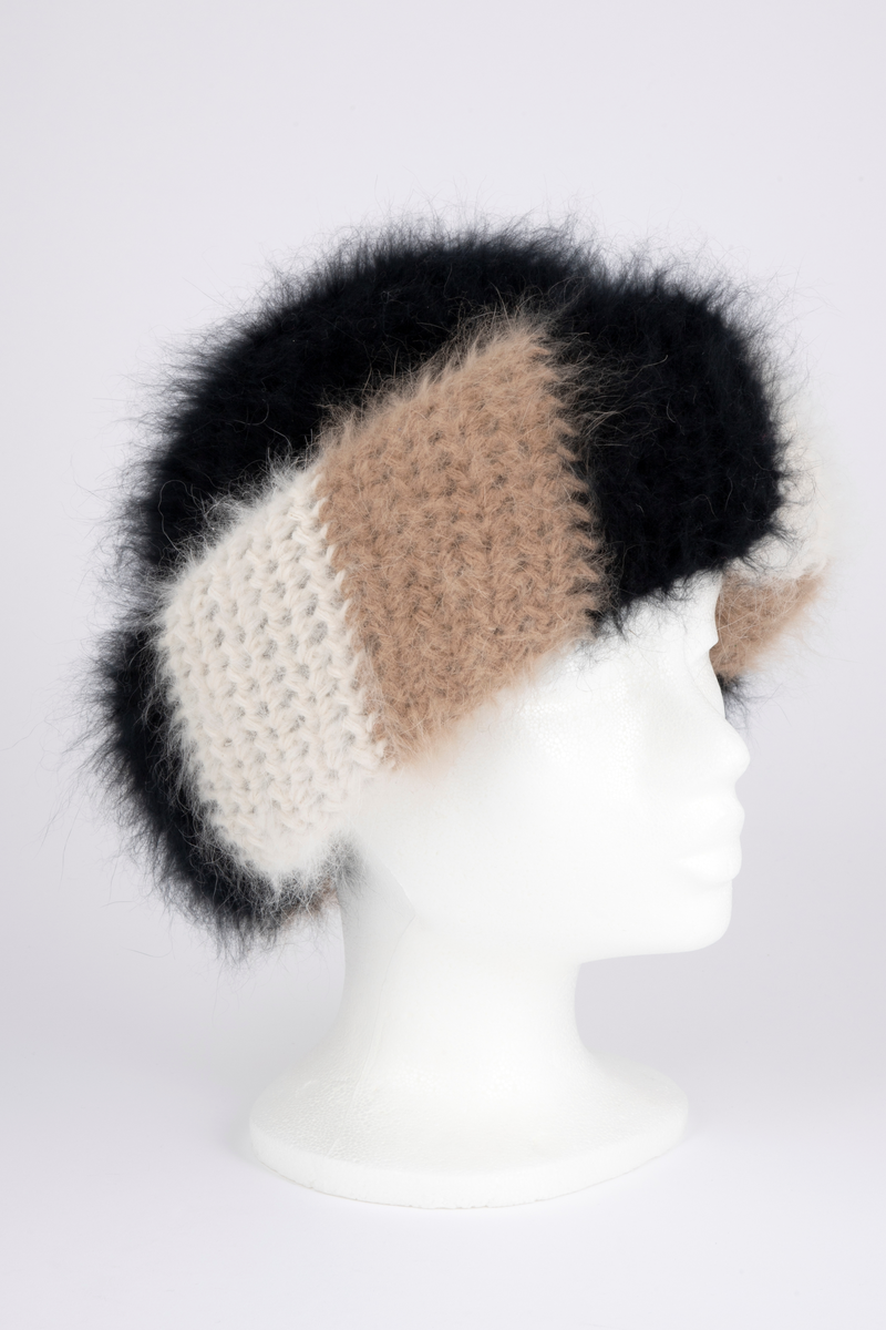Heklet, muligens strikket, lue av angoraull. Tettsittende, med rund pull og bred oppbrett. Både pull og oppbrett er dobbel; pullen svart og oppbretten diagonalstripet, med brede striper i vekselvis sauehvitt, beige og svart. Lodden og myk angoraull utvendig, mens pullen innvendig er mindre lodden, og antagelig ikke angora. Oppbretten er først laget dobbel, deretter sydd på pullen og brettet opp, slik at den danner 4 lag og blir stor og fyldig. Pullens to lag er ikke festet i hverandre unntatt nederst, der den har en isydd hattestrikk for å holde spensten.