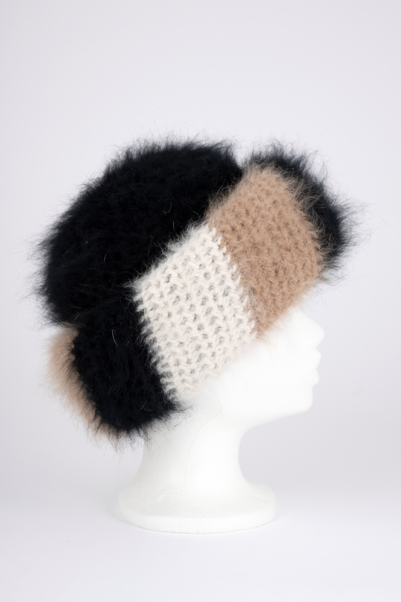 Heklet, muligens strikket, lue av angoraull. Tettsittende, med rund pull og bred oppbrett. Både pull og oppbrett er dobbel; pullen svart og oppbretten diagonalstripet, med brede striper i vekselvis sauehvitt, beige og svart. Lodden og myk angoraull utvendig, mens pullen innvendig er mindre lodden, og antagelig ikke angora. Oppbretten er først laget dobbel, deretter sydd på pullen og brettet opp, slik at den danner 4 lag og blir stor og fyldig. Pullens to lag er ikke festet i hverandre unntatt nederst, der den har en isydd hattestrikk for å holde spensten.