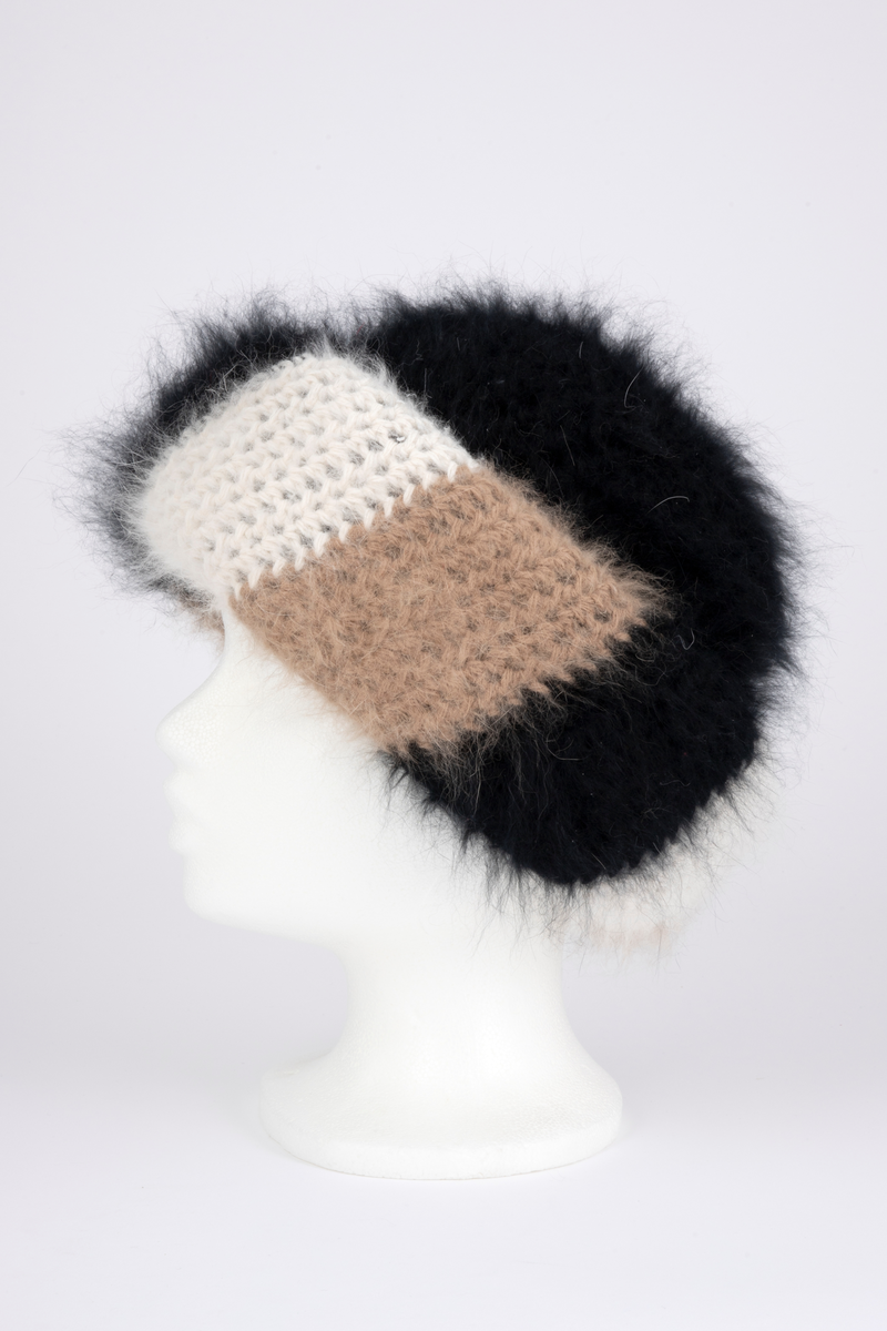 Heklet, muligens strikket, lue av angoraull. Tettsittende, med rund pull og bred oppbrett. Både pull og oppbrett er dobbel; pullen svart og oppbretten diagonalstripet, med brede striper i vekselvis sauehvitt, beige og svart. Lodden og myk angoraull utvendig, mens pullen innvendig er mindre lodden, og antagelig ikke angora. Oppbretten er først laget dobbel, deretter sydd på pullen og brettet opp, slik at den danner 4 lag og blir stor og fyldig. Pullens to lag er ikke festet i hverandre unntatt nederst, der den har en isydd hattestrikk for å holde spensten.