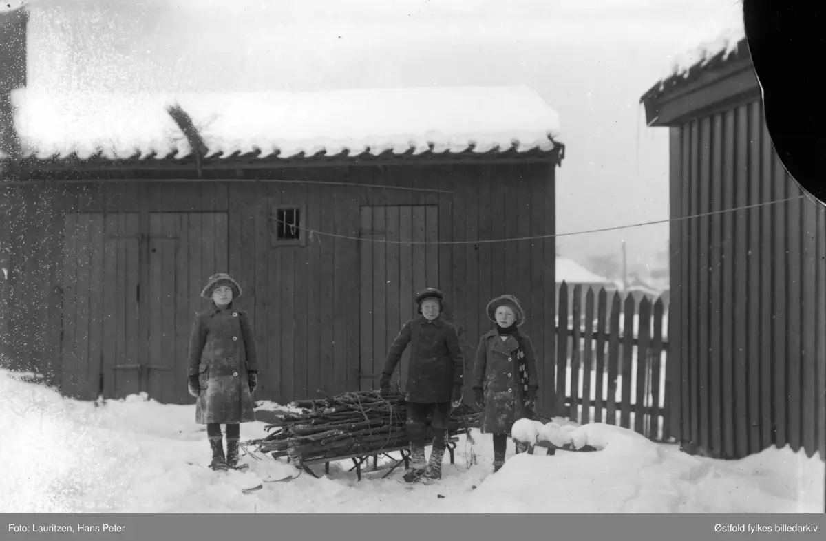 Ingertha Lauritzen  og Robert William Lauritzen  og Solveig Elvira Lauritze, barna til fotografen har hentet kvistved på kjelke.
Dette brenselet skulle for det meste brukes til den store bakerovnen de hadde. Det ble tre oppfyringer pr. dag. Barnas mor bakte opp 100 kg. mel hver dag og solgte brød og boller m.m.