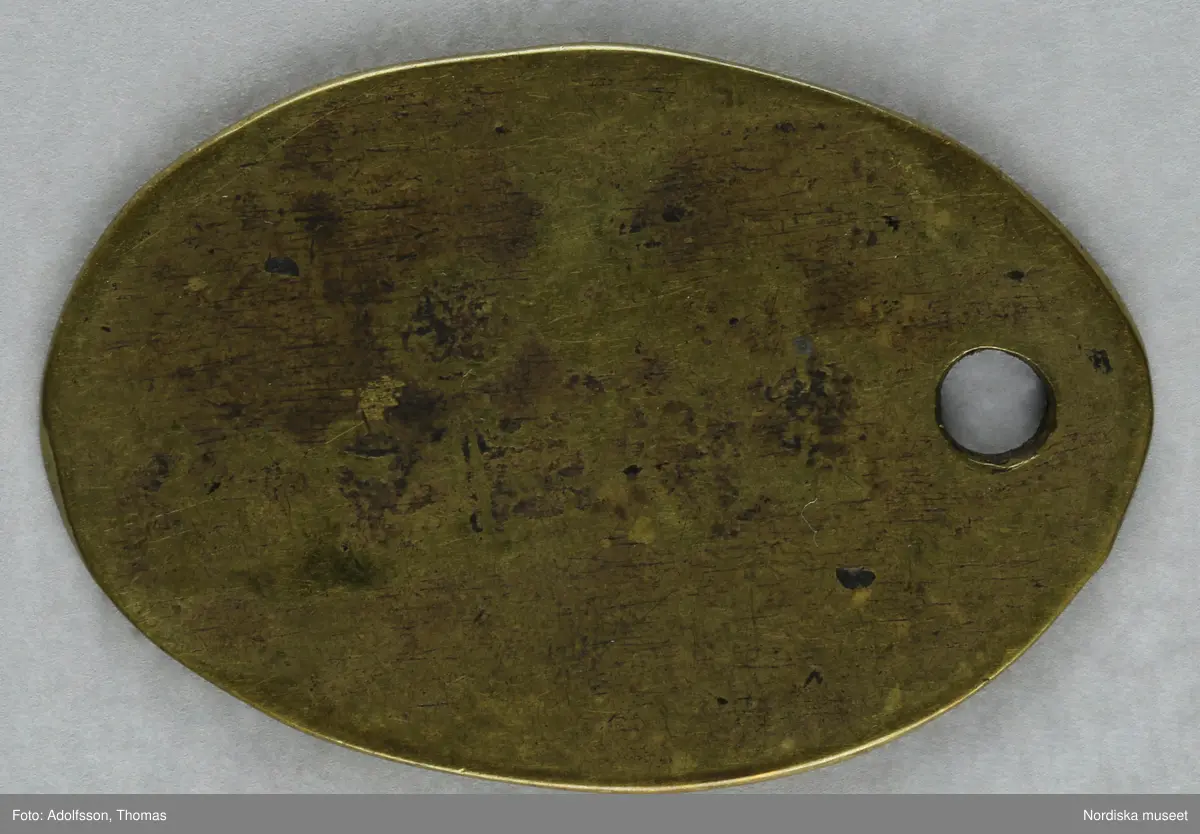 Pollett av mässing, oval. Text: 8 TUNNOR, 8:an omgiven av tre kronor.