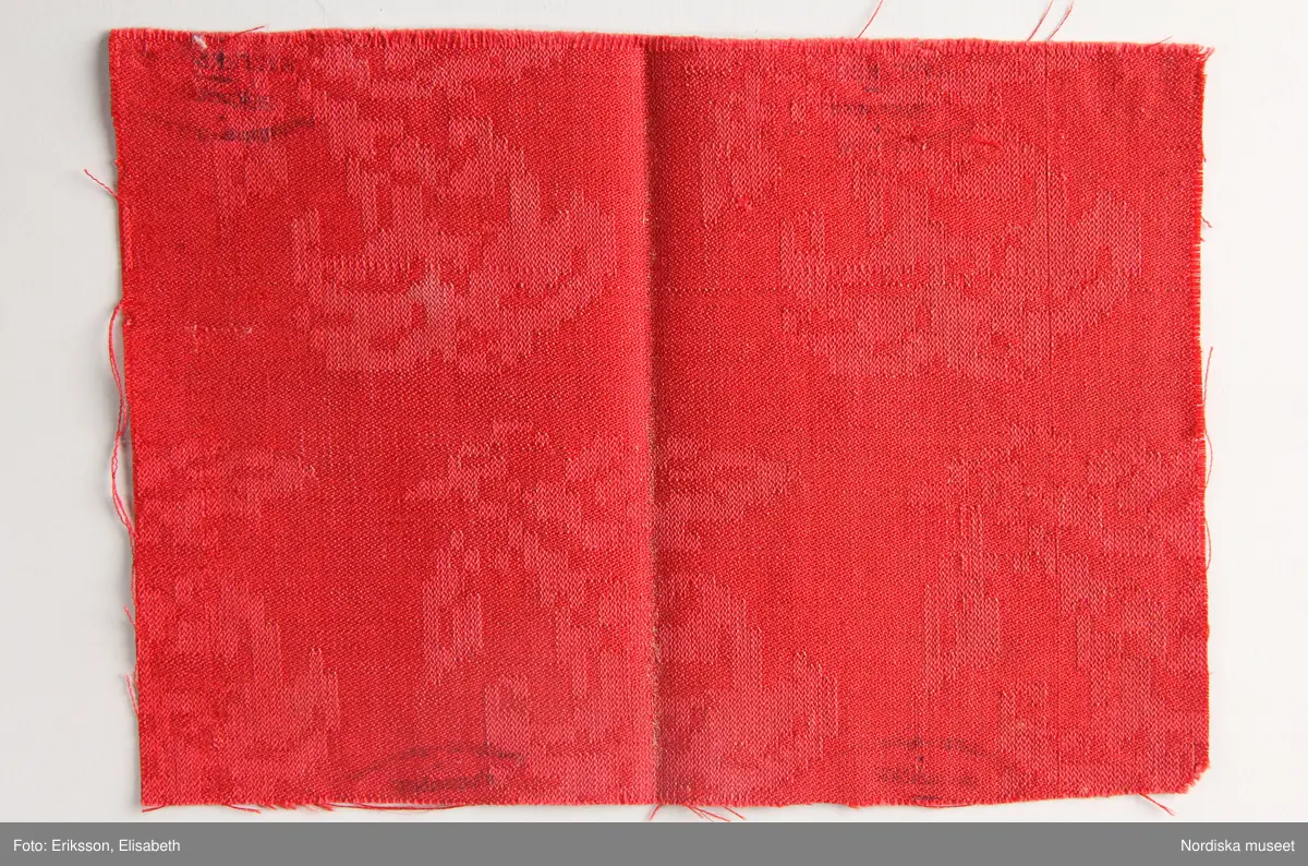 13 tygprover, varav  12 st på duktyg i förenklad damast enligt familjen Ekenmarks metod eller i rutig dräll på satin- eller kypertgrund. De flesta i rött/vitt eller blått/vitt, gult/vitt  och några helvita. I bomull, halvlinne och hellinne.
1 prov på rött möbeltyg i damast enligt Ekenmark med en upprepad snedställd blomma.
/Berit Eldvik 2012-03-06