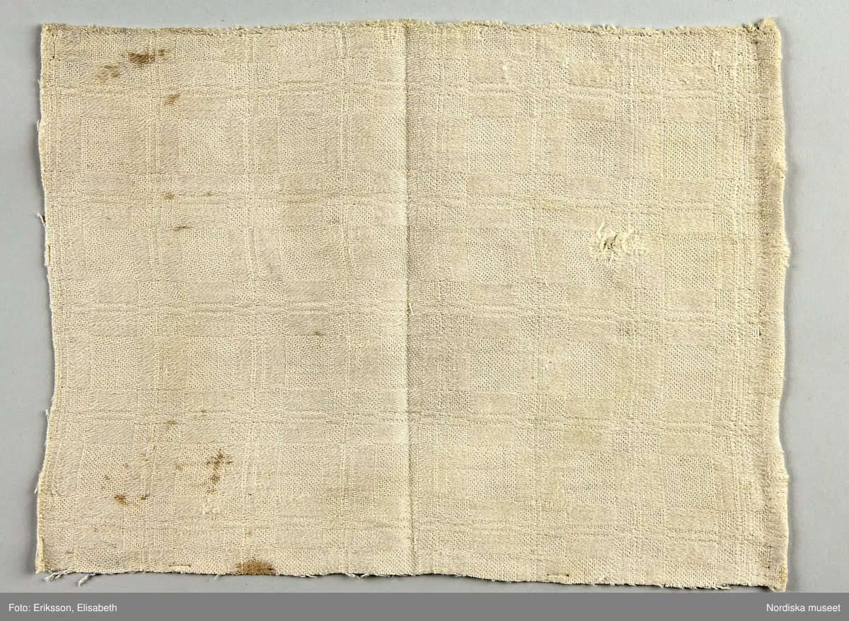 13 tygprover, varav  12 st på duktyg i förenklad damast enligt familjen Ekenmarks metod eller i rutig dräll på satin- eller kypertgrund. De flesta i rött/vitt eller blått/vitt, gult/vitt  och några helvita. I bomull, halvlinne och hellinne.
1 prov på rött möbeltyg i damast enligt Ekenmark med en upprepad snedställd blomma.
/Berit Eldvik 2012-03-06