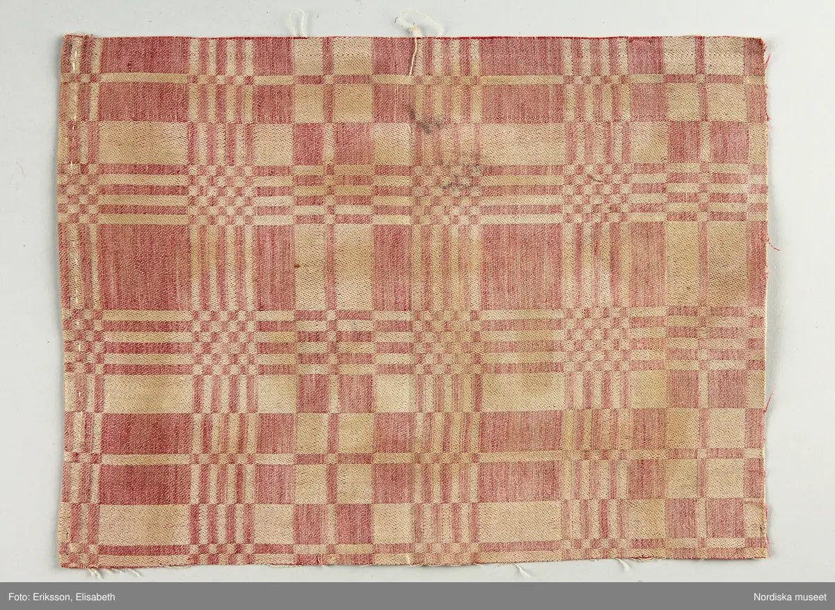 13 tygprover, varav  12 st på duktyg i förenklad damast enligt familjen Ekenmarks metod eller i rutig dräll på satin- eller kypertgrund. De flesta i rött/vitt eller blått/vitt, gult/vitt  och några helvita. I bomull, halvlinne och hellinne.
1 prov på rött möbeltyg i damast enligt Ekenmark med en upprepad snedställd blomma.
/Berit Eldvik 2012-03-06