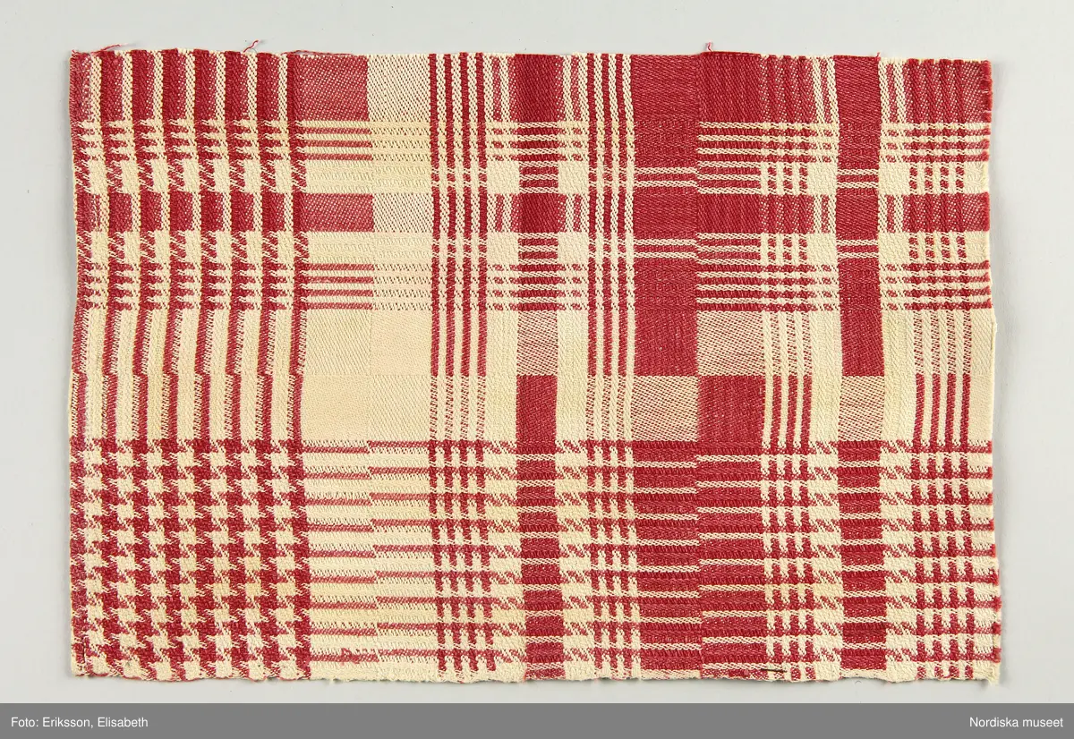 13 tygprover, varav  12 st på duktyg i förenklad damast enligt familjen Ekenmarks metod eller i rutig dräll på satin- eller kypertgrund. De flesta i rött/vitt eller blått/vitt, gult/vitt  och några helvita. I bomull, halvlinne och hellinne.
1 prov på rött möbeltyg i damast enligt Ekenmark med en upprepad snedställd blomma.
/Berit Eldvik 2012-03-06