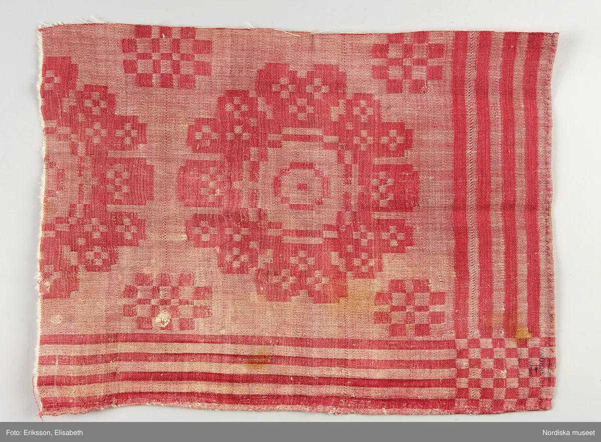 13 tygprover, varav  12 st på duktyg i förenklad damast enligt familjen Ekenmarks metod eller i rutig dräll på satin- eller kypertgrund. De flesta i rött/vitt eller blått/vitt, gult/vitt  och några helvita. I bomull, halvlinne och hellinne.
1 prov på rött möbeltyg i damast enligt Ekenmark med en upprepad snedställd blomma.
/Berit Eldvik 2012-03-06