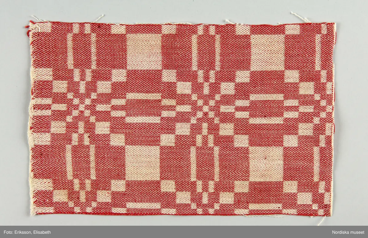 13 tygprover, varav  12 st på duktyg i förenklad damast enligt familjen Ekenmarks metod eller i rutig dräll på satin- eller kypertgrund. De flesta i rött/vitt eller blått/vitt, gult/vitt  och några helvita. I bomull, halvlinne och hellinne.
1 prov på rött möbeltyg i damast enligt Ekenmark med en upprepad snedställd blomma.
/Berit Eldvik 2012-03-06