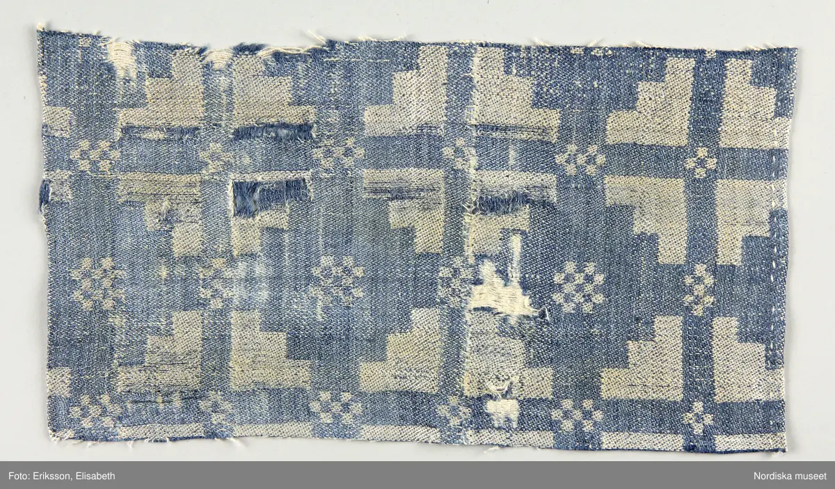 13 tygprover, varav  12 st på duktyg i förenklad damast enligt familjen Ekenmarks metod eller i rutig dräll på satin- eller kypertgrund. De flesta i rött/vitt eller blått/vitt, gult/vitt  och några helvita. I bomull, halvlinne och hellinne.
1 prov på rött möbeltyg i damast enligt Ekenmark med en upprepad snedställd blomma.
/Berit Eldvik 2012-03-06