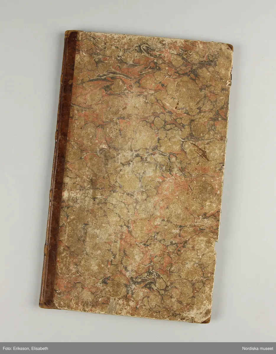 Inbunden bok med brunmarmorerade pärmar och rygg av brunt skinn. På första sidan skrivet för hand: "Wäf-Mönster-Bok för Demoisellerne Ekenmark tillhörig Anna Lithén Skara den 27 nov. 1826."
Innehåller 27 damast-och drällnotor av de vanliga slag som lärdes ut på Ekenmarks ambulerande vävkurser. Mönstrens namn påskrivna.
Bak i boken finns vävnotor och 17 tygprover på småmönstrade mångskaftade  vävnader som också lärdes ut på kurserna., samma som finns i deras tryckta läroböcker, t.ex.: nr 52 (delvis) Mönster till faconer utan veck med en bom ( hålkrus). Nr 21, stjärntyg nr 24,  blombård nr 22, wecktyg med vandringsman nr 20, 2 schalettemönster, Wästtygsmönster nr 57, Förgätmigejmönstret nr 27 samt nr. 44 2 prover.
Boken i gott skick.
Har  tillhört vävlärarinnan Johanna Brunsson, som hade känd vävskola för utbildning av vävlärare i Stockholm. Givaren  Alma Jacobbson var hennes systerdotter som tog över verksamheten efter hennes död.
/Berit Eldvik 2012-02-28