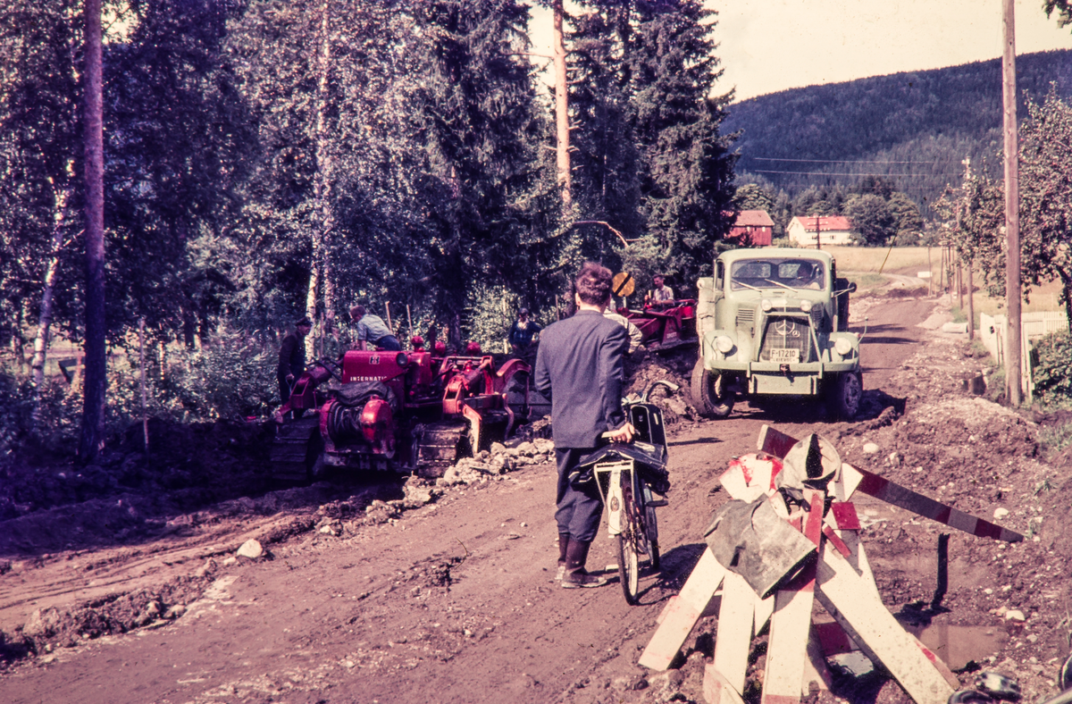 Utbedring av veien (Fv. 32-Tuftveien) mot Holmestrand en gang på 60 tallet. 
Til venstre bak skogen festlokalet Hallen. 
Rett fram sees jordet som senere  ble Solvangfeltet.