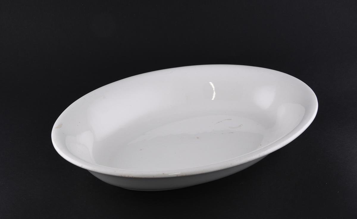 Hvitt ovalt serveringsfat laget i steintøy.