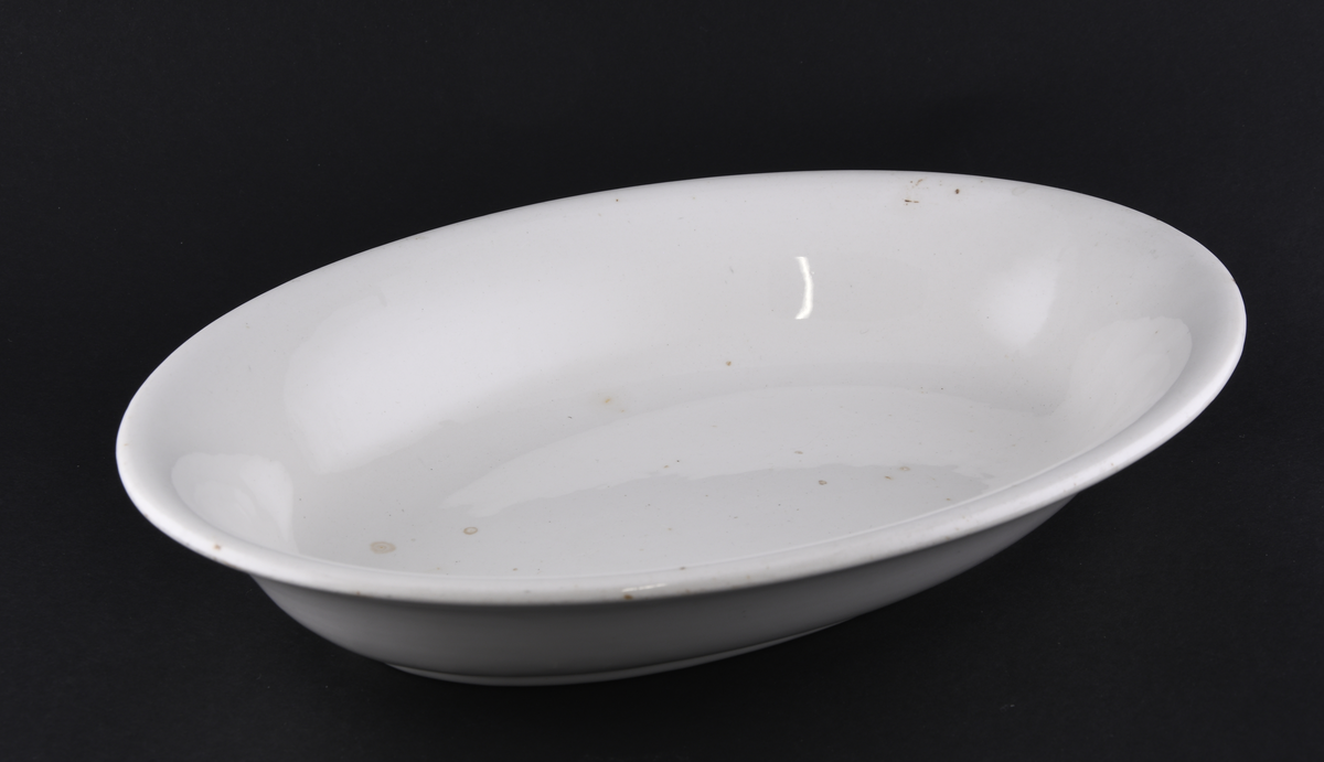 Hvitt ovalt serveringsfat laget i steintøy.
