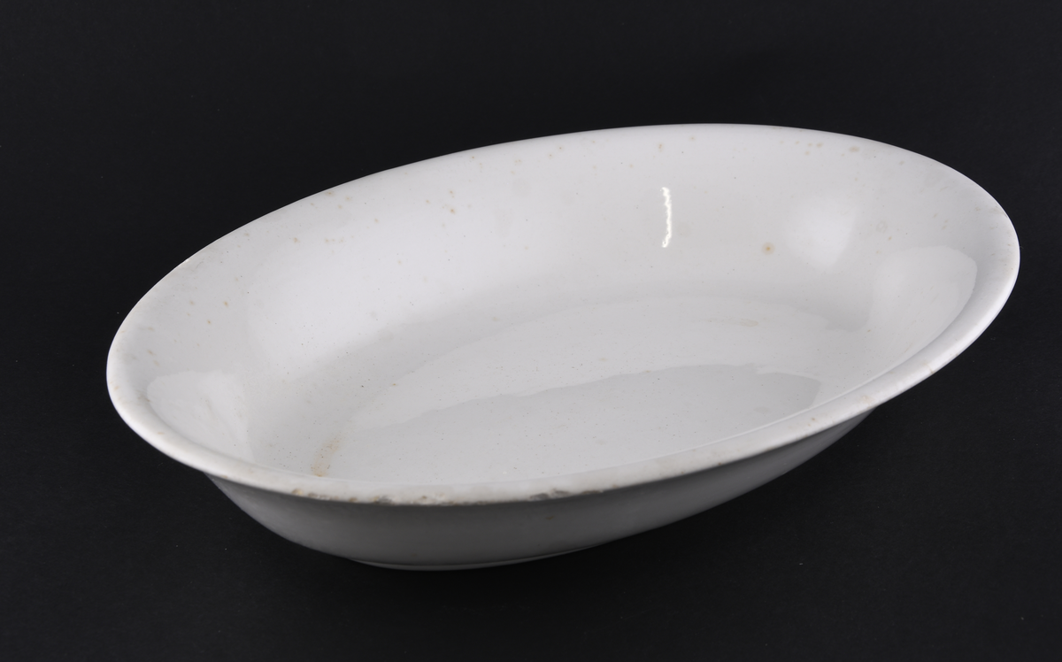 Hvitt ovalt serveringsfat laget i steintøy.