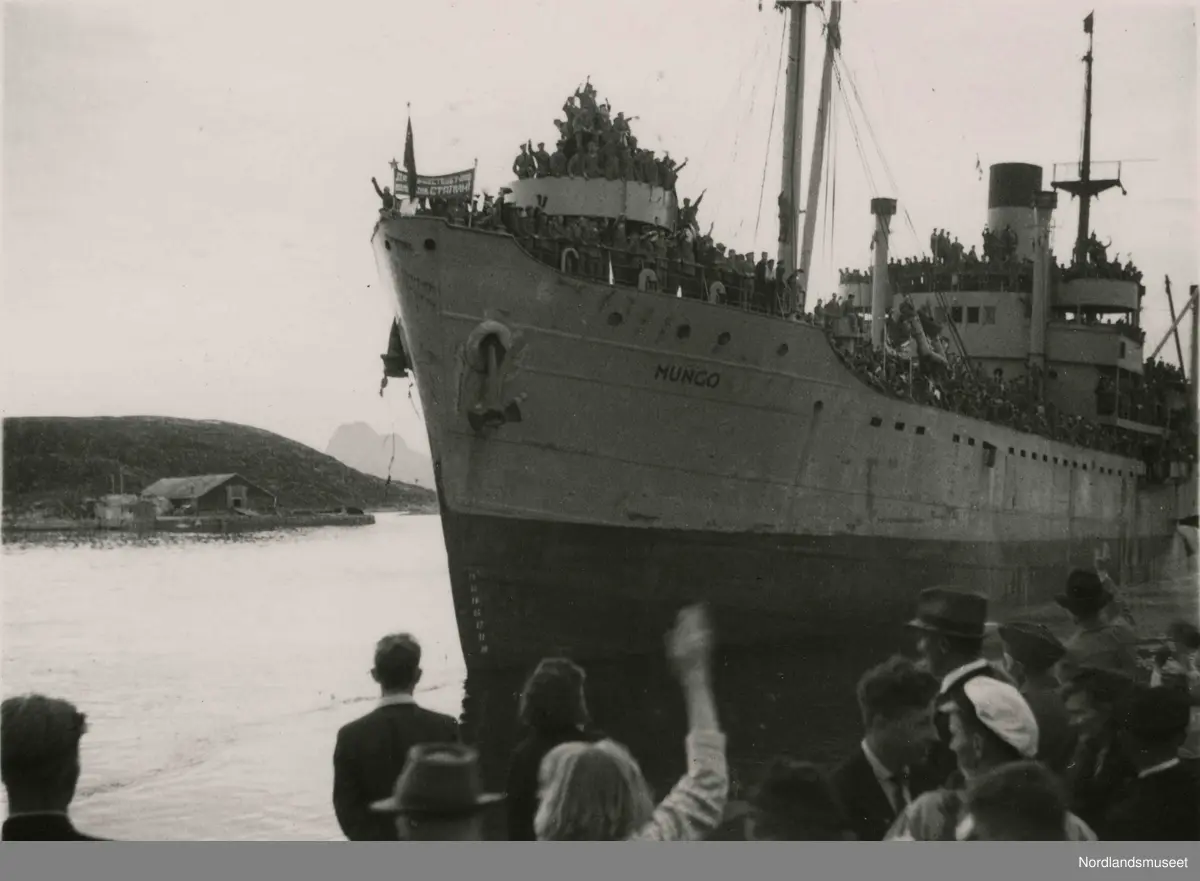Et stort skip med mange mennesker på dekk.  "Mungo". Trolig bilde av de sovjetiske krigsfangers avskjed. Bilde tatt i Bodø under feiring av freden etter okkupasjonen 1945.