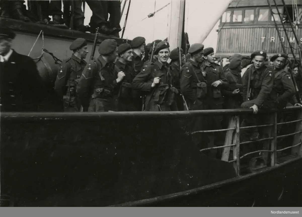 Mange soldater ombord i et skip. Navnet på skipet begynner med "Troms". Bilde tatt i Bodø under feiring av freden etter okkupasjonen 1945.