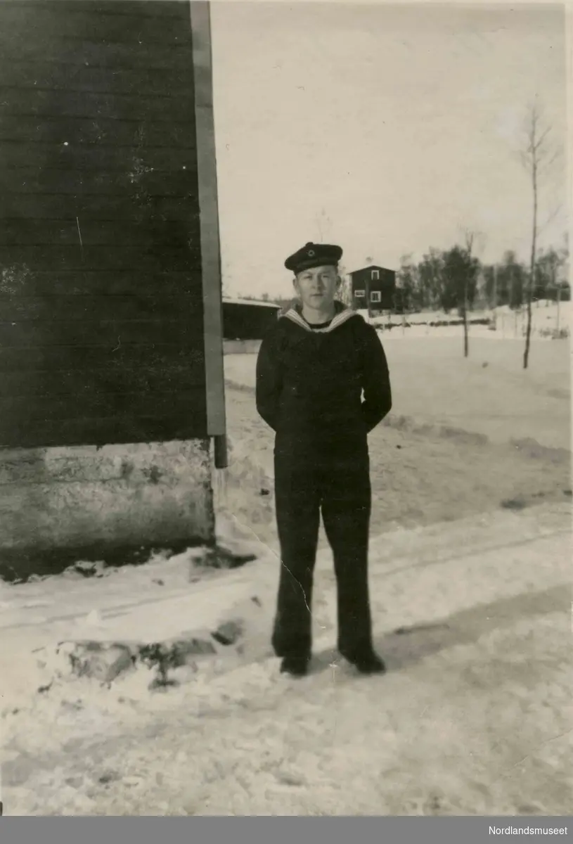 En ung mann i matrosuniform står utendørs. Snø på bakken. Kan være Odd Mercelius Hunstad.