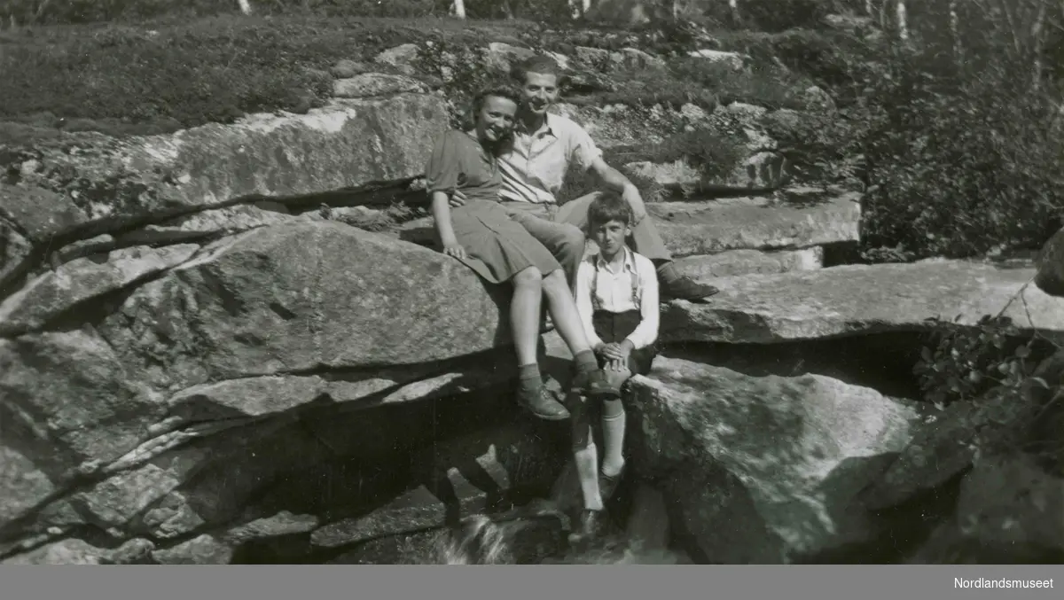 Fire barn/ungdommer sitter på en stein. Bildetekst: "Sommer i Nygårdsjøen 1942. Frivillig evakuering. På berget. Solveig, Arthur og Svein.