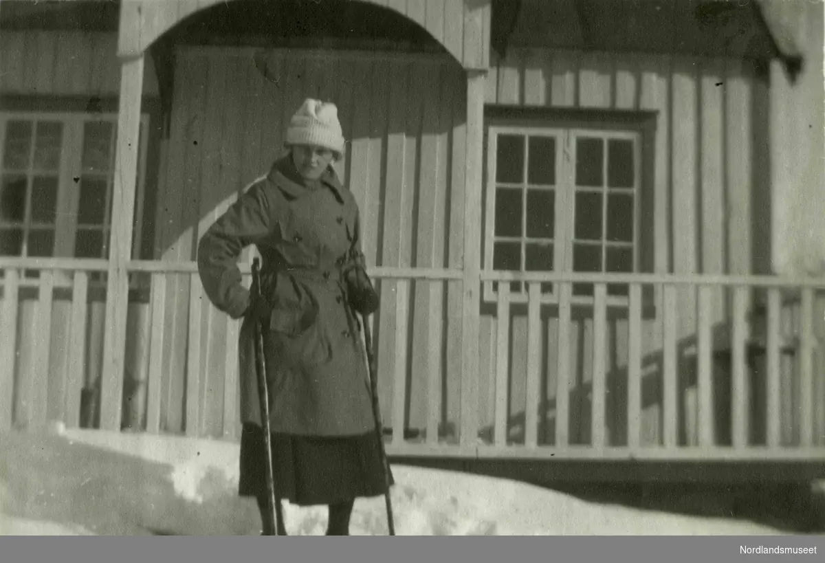 En kvinne på ski foran et hus.