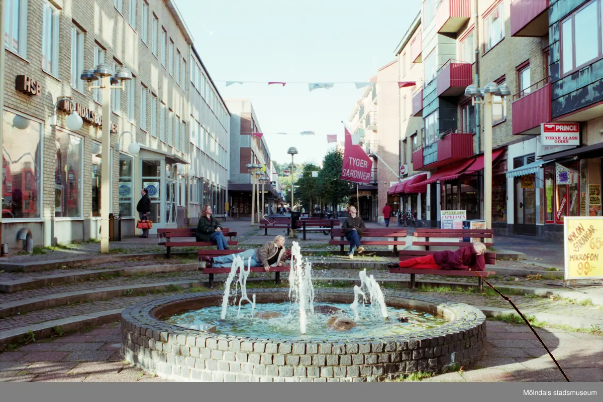En fontän i början av Brogatan. Mölndalsbro i dag - ett skolpedagogiskt dokumentationsprojekt på Mölndals museum under oktober 1996. 1996_1042-1051 är gjorda av högstadieelever från Kvarnbyskolan 9C, grupp 2. Se även 1996_0913-0940, gruppbilder på klasserna 1996_1382-1405 samt bilder från den färdiga utställningen 1996_1358-1381.